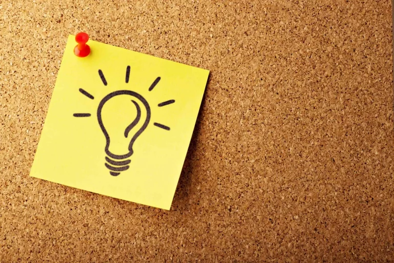 Post-it jaune avec dessin d'ampoule sur tableau liège