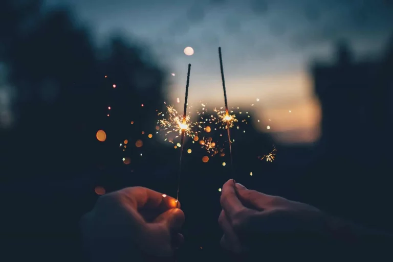 Deux cierges magiques scintillant dans la nuit, tenus délicatement dans les mains.