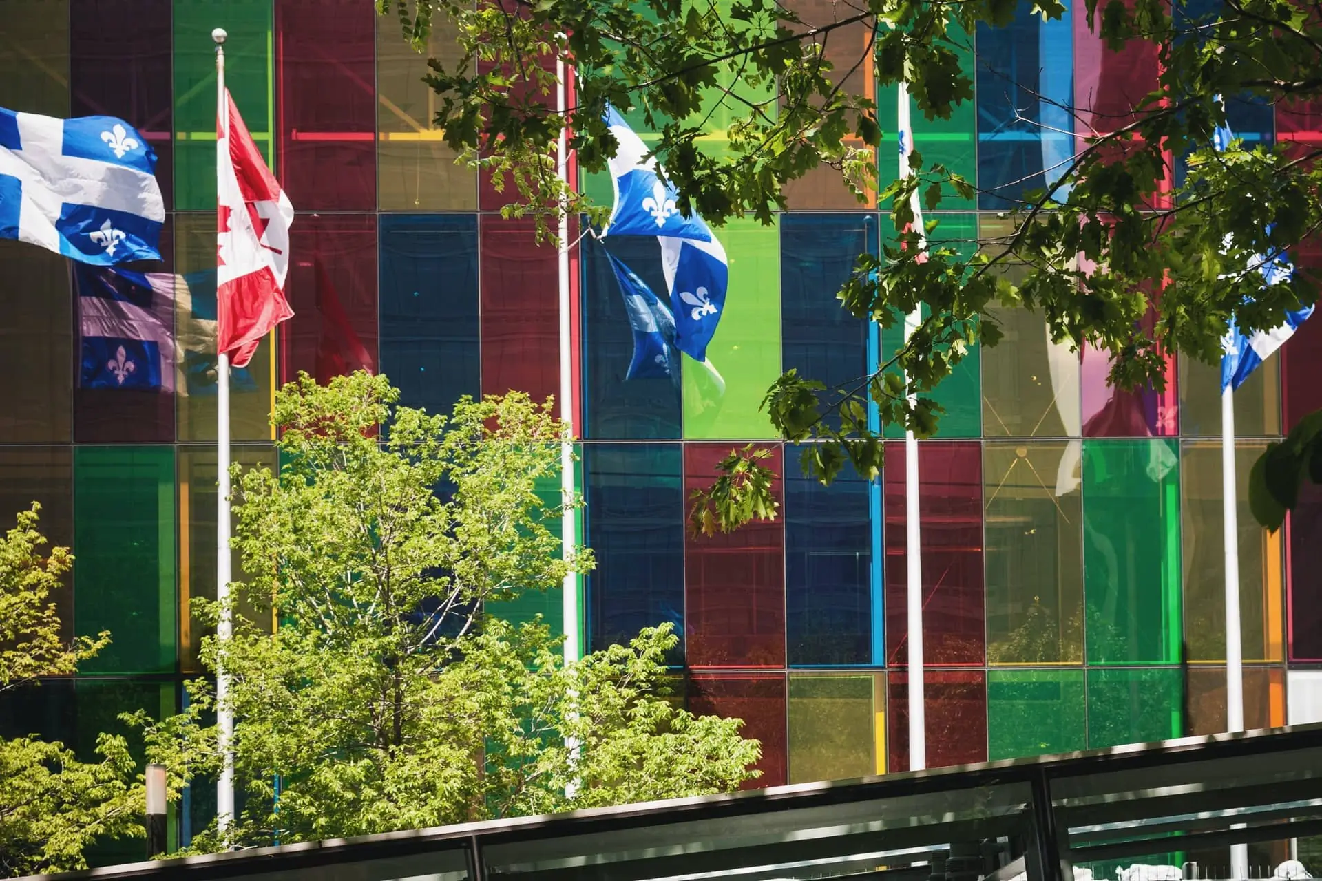 Drapeaux et façade colorée entre les arbres avec les 2 drapeaux du québec et du canada