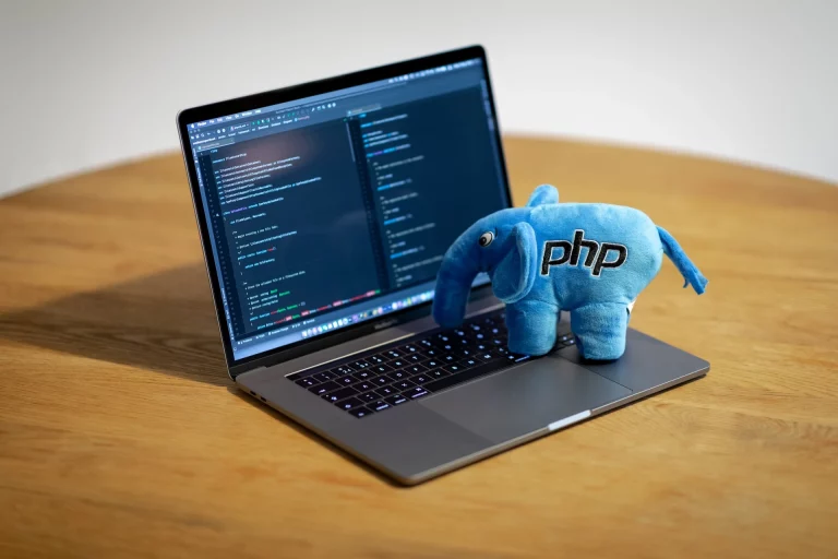 Peluche éléphant PHP posée sur un ordinateur portable, avec du code affiché à l'écran.