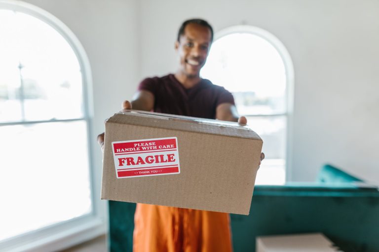 Homme remettant un colis fragile souriant