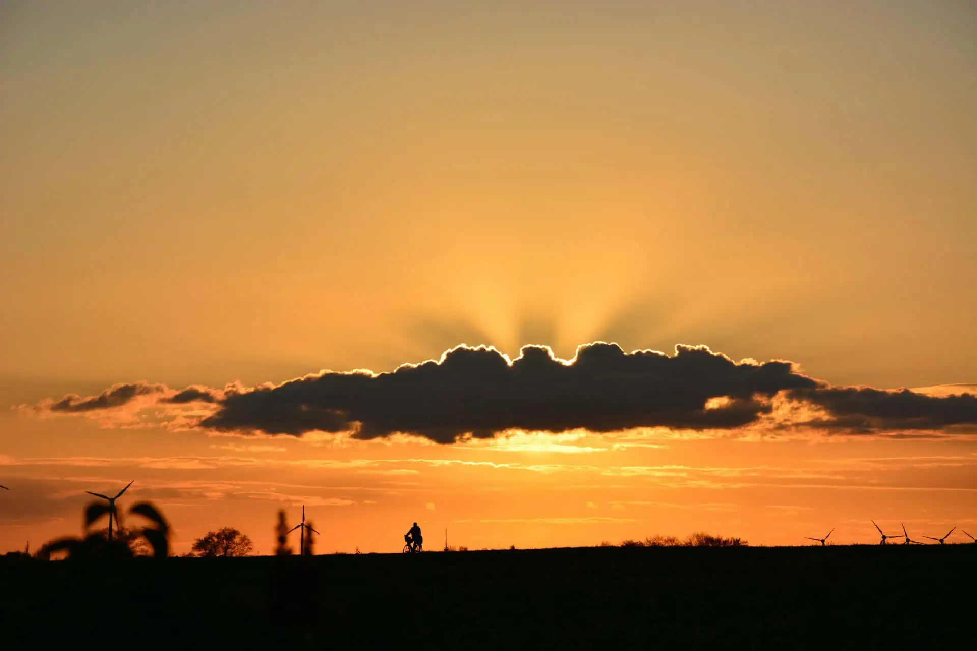 Cycliste au coucher de soleil avec nuages lumineux