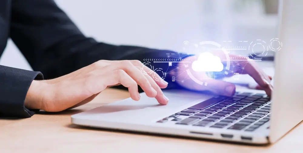 Personne travaillant sur un ordinateur portable avec des icônes de cloud computing