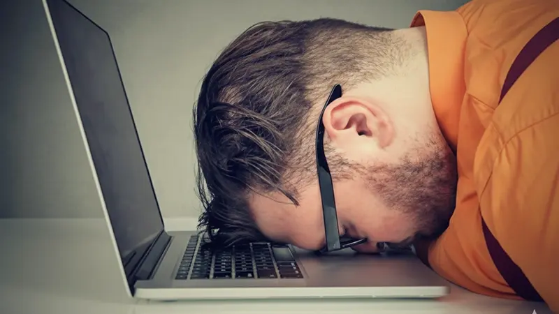 Homme épuisé dormant sur son ordinateur portable
