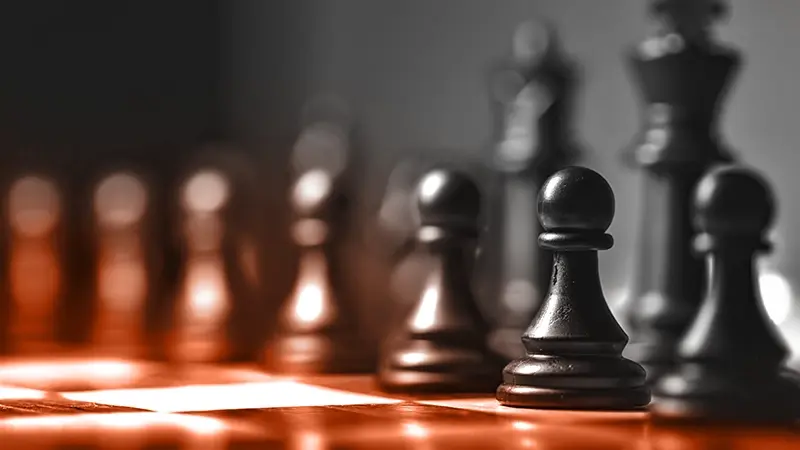 Pièces d'échecs sur échiquier, lumière dramatique.