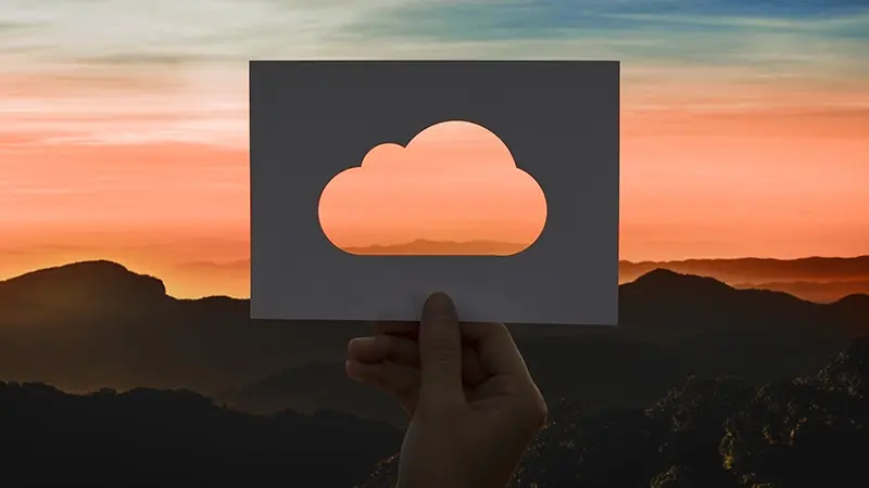 Main tenant une découpe nuage devant un coucher de soleil