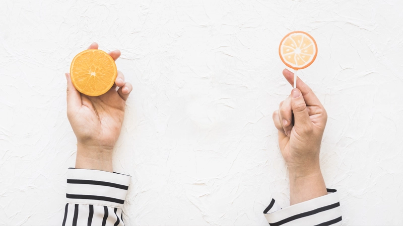 Main tenant une orange et une sucette orange
