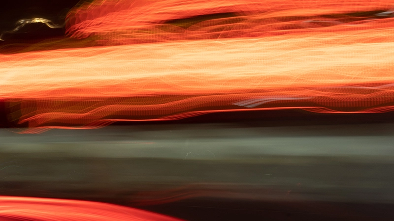 Traînées lumineuses orange et rouges sur fond sombre urbain